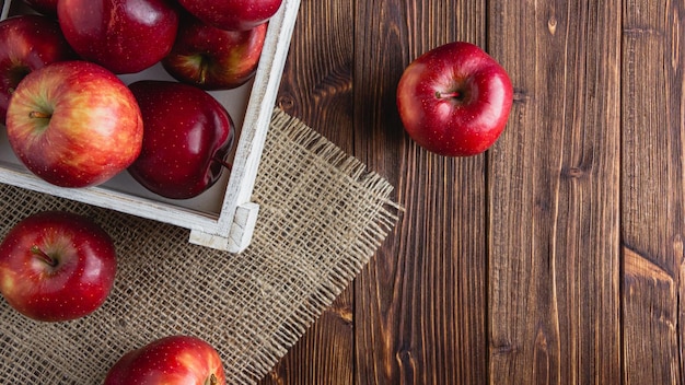 Photo red apples in a crate on a wooden background