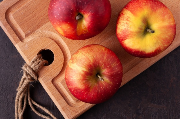 Red apples lie on a wooden board close up