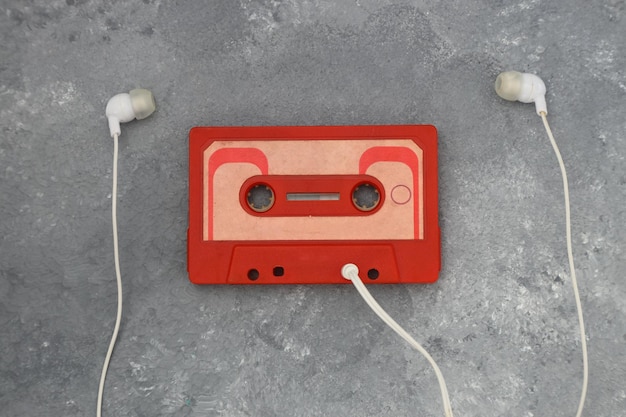 Red audio cassette and cassette pleer with headphones on a green background Party 90s concept