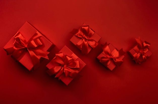 Red background with gift boxes ribbons bows Preparation for holidays Christmas Valentines day birthday New Year concept Top view