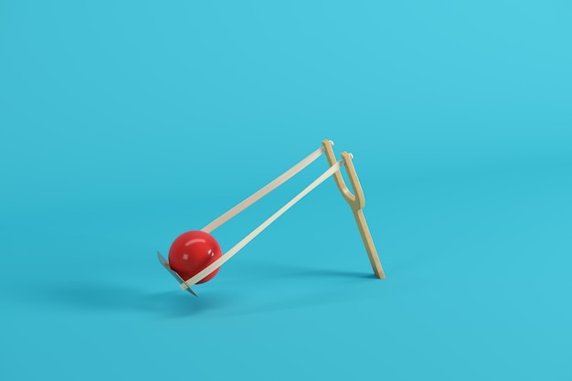 Red ball in a slingshot on blue background