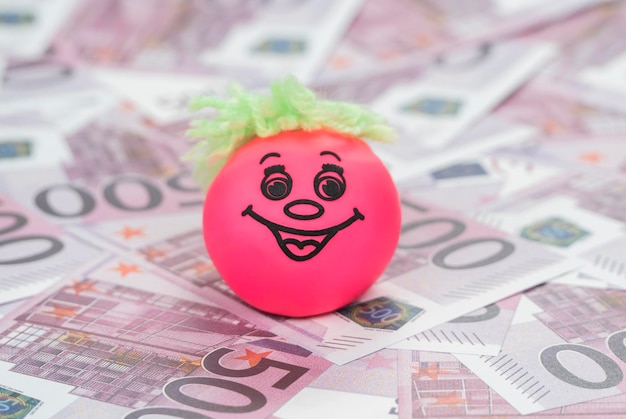 red ball with a smiley on the money with face value of five hundred euro