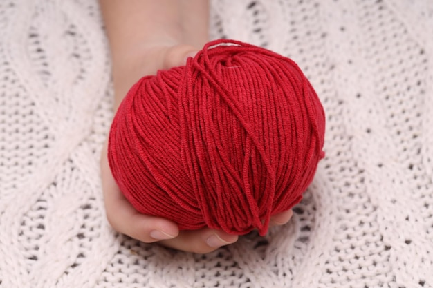 Red ball of wool in hands on the background of a white knitted tablecloth High quality photo