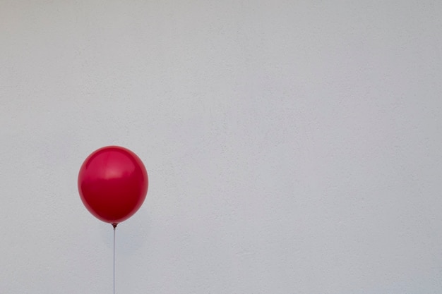 Red balloon against a white wall. Sign of Depression and Anxiety