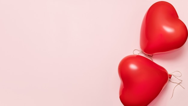 Red balloons in shape of heart on pale pink background. Valentines day concept. Banner, copy space