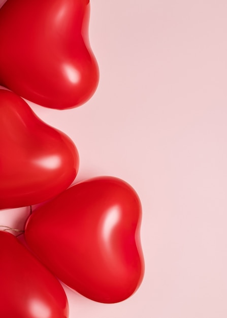 Red balloons in shape of heart on pale pink background. Valentines day concept.