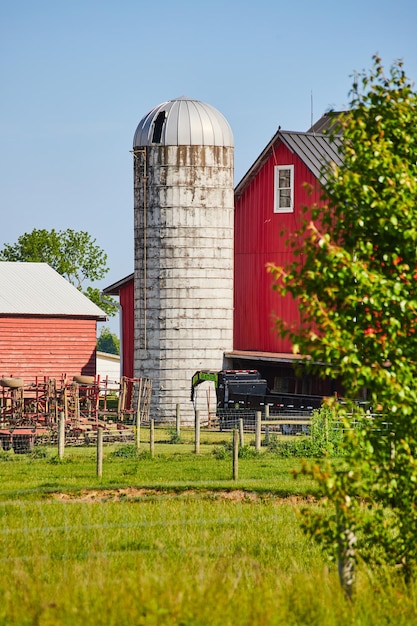 Red barn with green field pasture and white silo