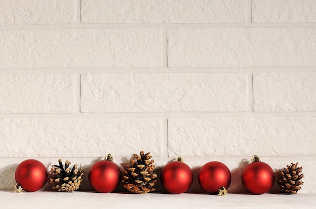 Red baubles with pine cones on white bricks background