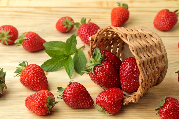 Red berry strawberries in a wicker basket on a natural wooden table