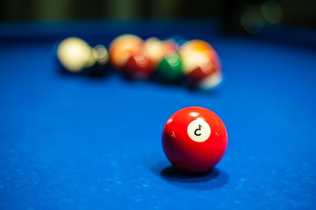 a red billiard ball is lying on a table with a background of blurred balls