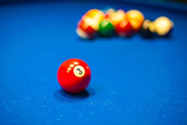 a red billiard ball is lying on a table with a background of blurred balls