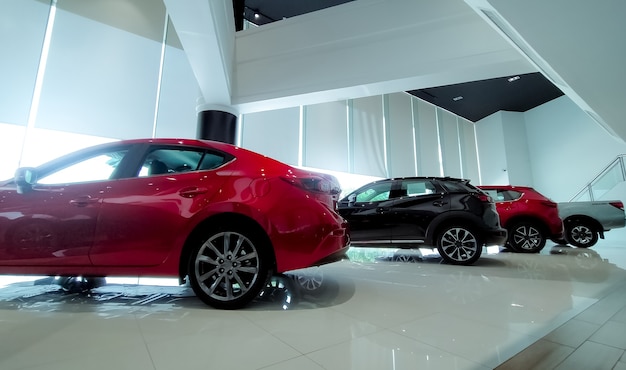 Red and black car parked in modern showroom. Car dealership and auto leasing concept. Automotive industry. Modern luxury showroom. New car parked in showroom. Electric automobile. Showroom interior.