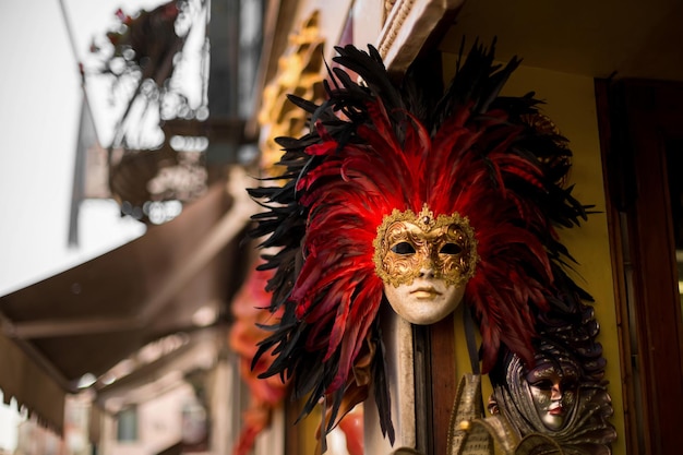 A red and black carnival mask is displayed on a building.