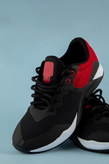 Red and black tennis shoes for running with a blue background and space for text