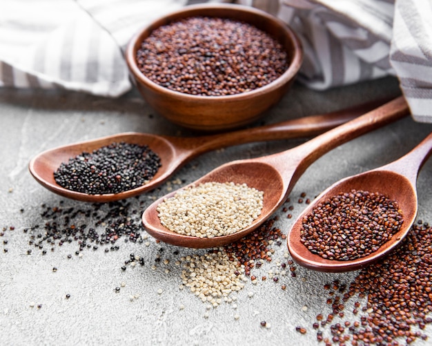 Red, black and white quinoa seeds on a concrete background