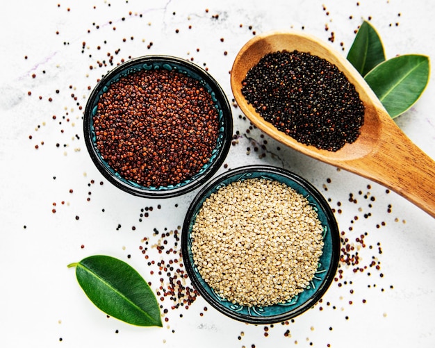 Red, black and white quinoa seeds on a concrete table