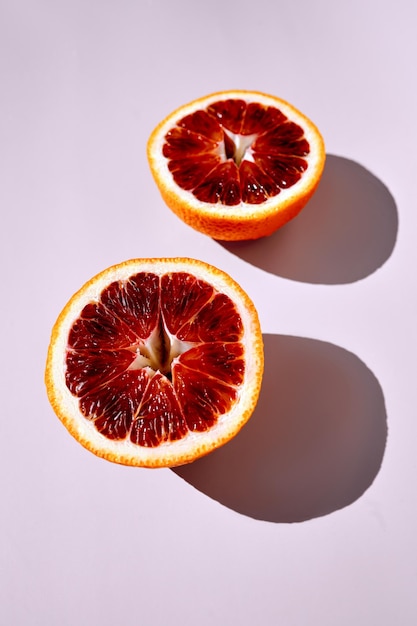 Photo red blood orange half isolated on light pink background sun light long shadow vertical background