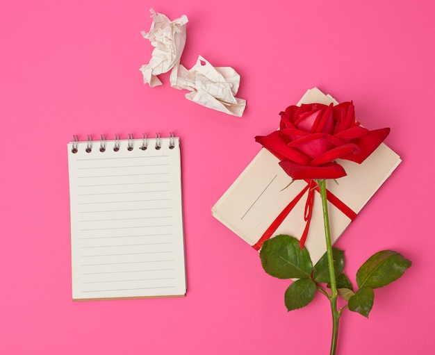 Red blooming rose, a stack of vintage paper cards and paper notebook