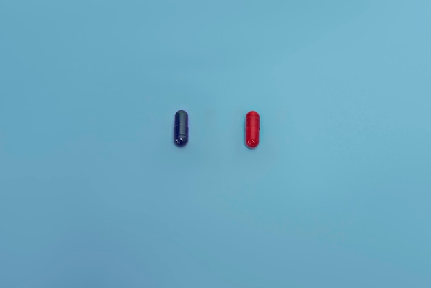 Red and blue pills isolated on blue