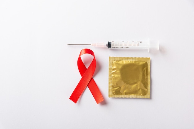 Red bow ribbon symbol HIV AIDS cancer awareness condom and syringe with shadows