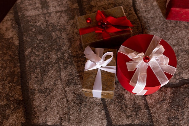 A red box with a white ribbon is on the floor next to a red box with a white ribbon.