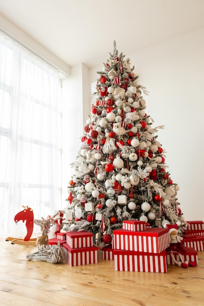 Red boxes with gifts Christmas tree with white and red decorations Indoor Christmas design big pine tree festive home interior