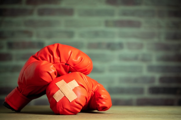 Red boxing gloves on wooden table and brick wall at the sport gym