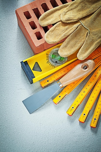 Red brick protective gloves plastering trowel construction level wooden meter on concrete background bricklaying concept