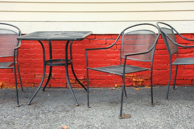 A red brick wall with a black table and chairs.