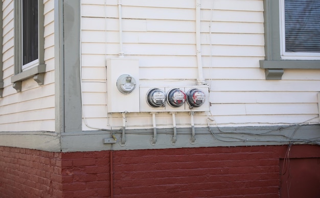 A red brick wall with a bunch of electrical meters on it.