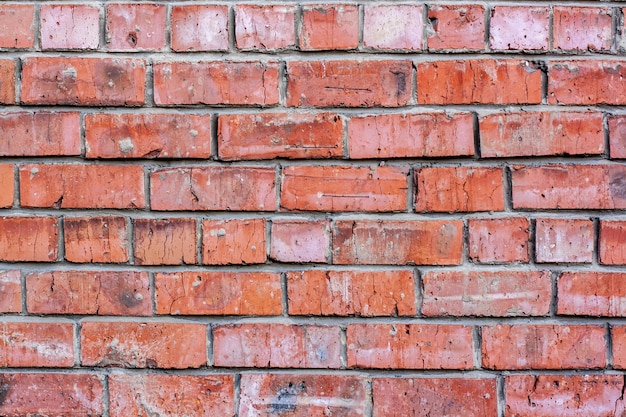 Red brick wall with very old and cracked stones. Mortar stained texture.