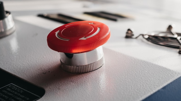 A red button on a white surface with a black background and a black and white piece of paper.