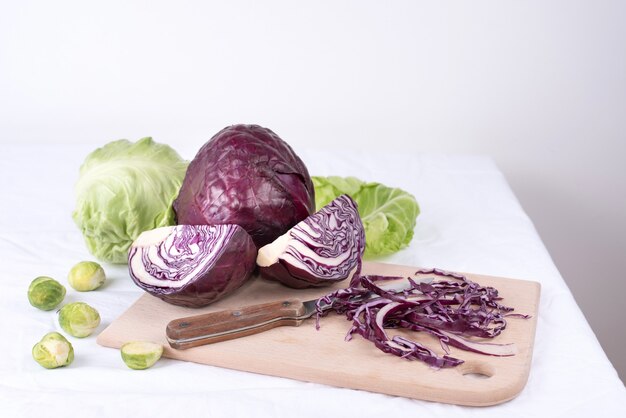 Red cabbage, early cabbage head, brussels sprouts on a cutting board with a knife