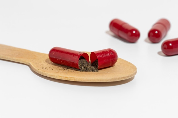 Red capsules of vitamins pills or medicine ashwagandha brahmi on the wooden spoon