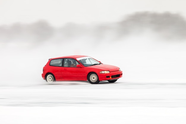 Red car moving on ice making lots of ice splashes