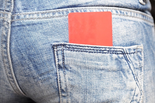 A red card in a back pocket of a pair of blue jeans