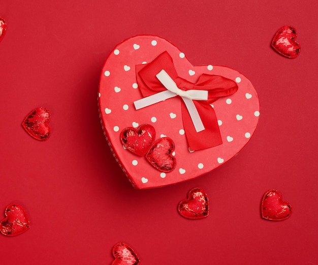 Red cardboard box with a gift on a red background top view