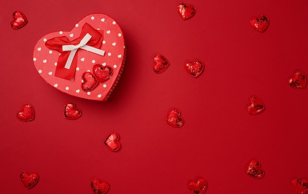 Red cardboard box with a gift on a red background top view