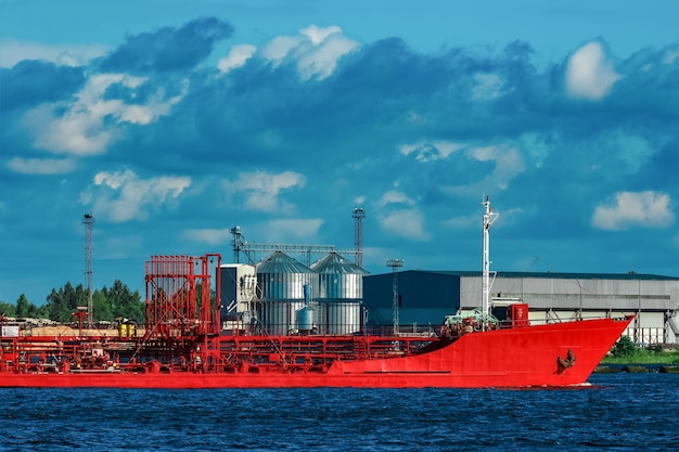 Red cargo tanker ship moving by the river