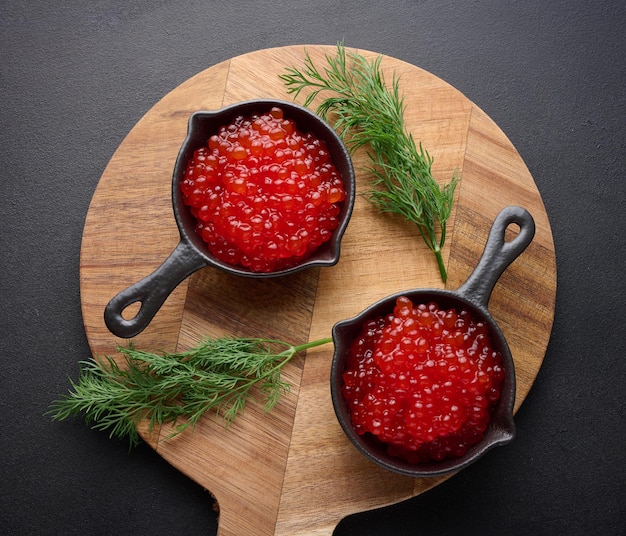 Red caviar in a black mini frying pan on the table top view concept of luxury and gourmet cuisine