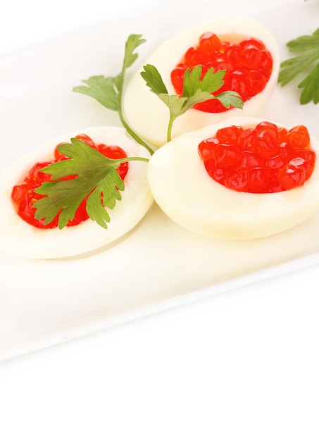 Red caviar in eggs on white plate isolated on white