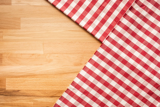 Red checkered fabric on wood table background.For decoration key visual layout