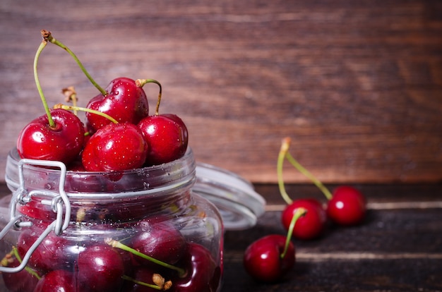 Red cherries in a glass jar. Sunny summer and harvest concept. Cherry macro. 