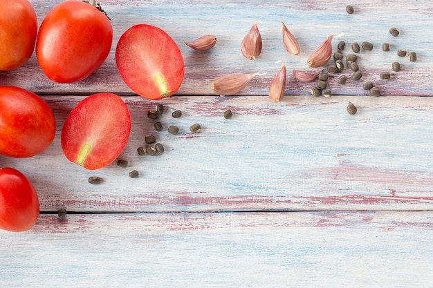 Red cherry plum tomatoes in stainless bowl on wood table background