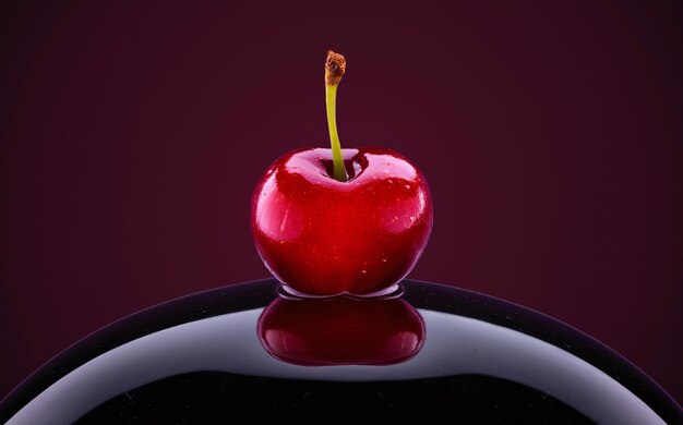 a red cherry with a stem on a black chocolate