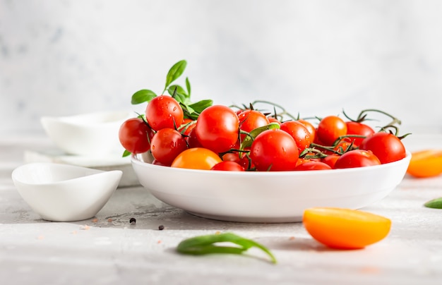 Red cherry and yellow tomatoes with baby spinach on the white plate