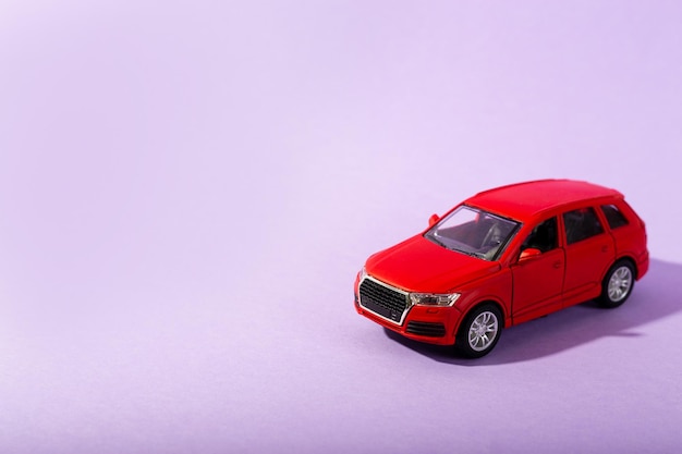 Red children's toy car model isolated on purple background close up