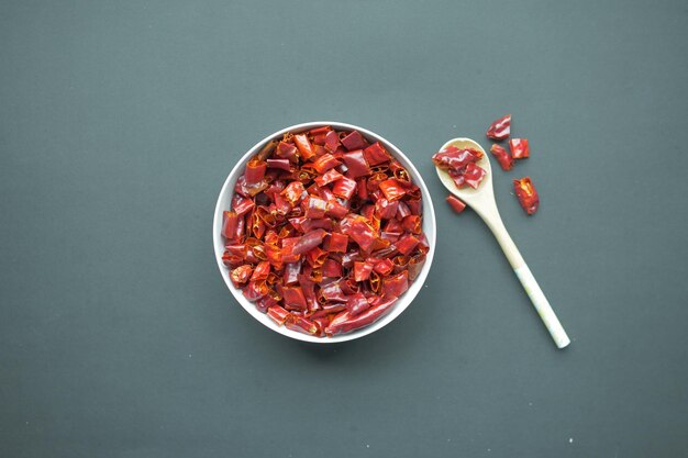 Red chili pepper flakes in a bowl on black background