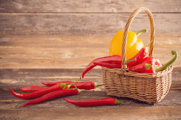 red chili peppers in basket on old wooden table