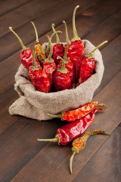 Red chili peppers in a canvas sack on wooden table